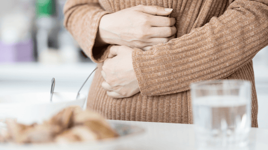 woman holding stomach for inflammation with mushrooms in foreground